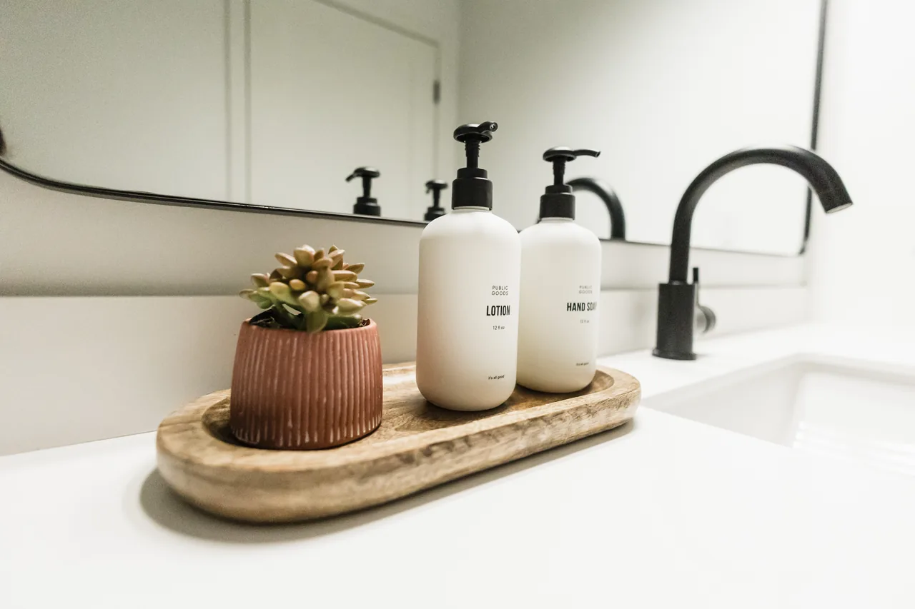 Vanity tray with lotion and hand soap bottles beside a small succulent on a white quartz countertop
